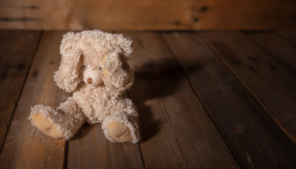 A soft toy rabbit sitting quietly on wooden floorboards